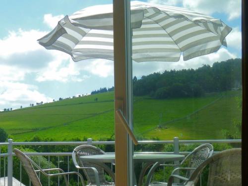 a table and chairs with an umbrella and a field at Modern Apartment in Willingen near Ski Lift in Willingen