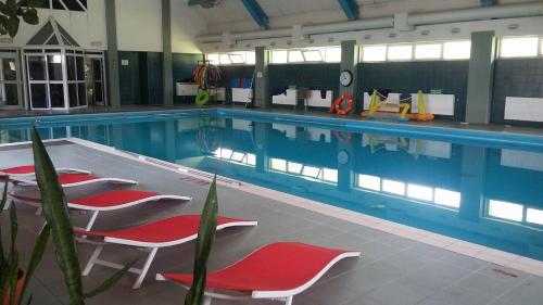 a large swimming pool with red chairs in it at Geovita Muszyna in Muszyna