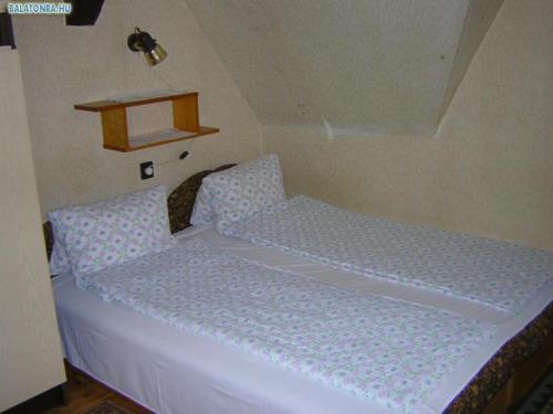 シオーフォクにあるSiófok Aranypartの白いマットレスと棚が備わる客室のベッド1台分です。