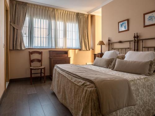 a bedroom with a bed and a chair and a window at Casa Maravilla in Faro de Peñas
