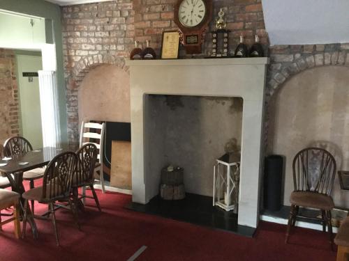 a living room with a fireplace with a table and chairs at The Huntsman in Cheadle