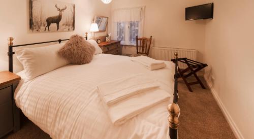 a bedroom with a bed with white sheets and a deer picture at Blue Bell Cottage in Ollerton
