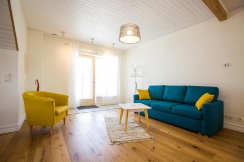 a living room with a blue couch and yellow chairs at Haapsalu Old Town Apartments in Haapsalu