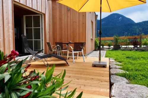 una terraza de madera con mesa y sombrilla en Ferienwohnung Almflair Chalet, en Thiersee