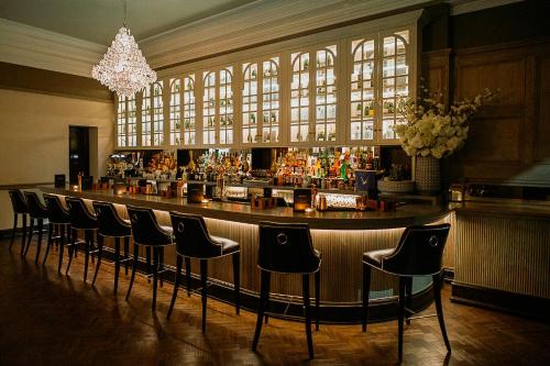a bar with a row of chairs in a room at County Hotel & County Aparthotel Newcastle in Newcastle upon Tyne