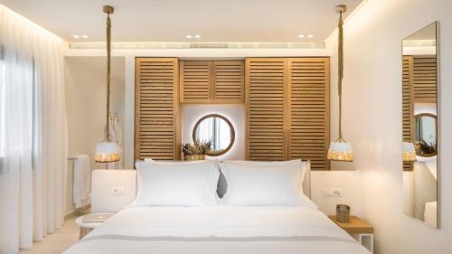 a bedroom with a white bed and a mirror at 18 Grapes Hotel in Agios Prokopios