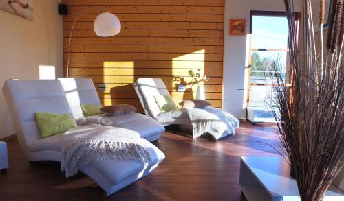 - deux chaises blanches dans une chambre dotée de murs en bois dans l'établissement VVF Les Fontaines des Vosges, à Saales
