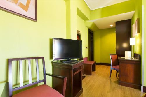 a living room with a flat screen tv and chairs at Hotel Carlos V in Granada