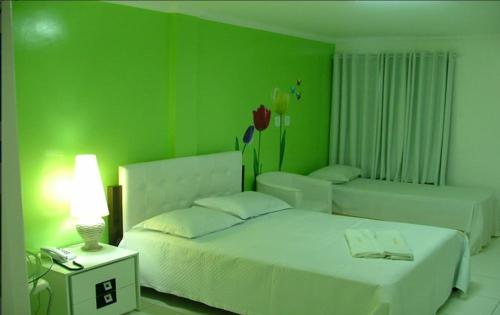 a green bedroom with a bed and a table with a lamp at Hotel Porthal da Ilha- Paulo Afonso-Ba in Paulo Afonso