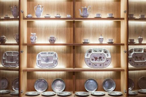 a shelf filled with plates and utensils at Boutique & Gourmet Hotel Orso Grigio in San Candido