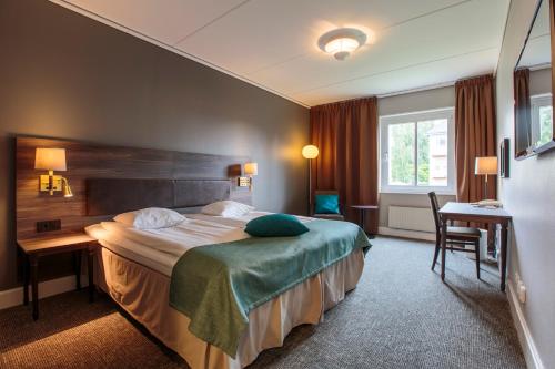 于默奧的住宿－克拉利奧烏曼連鎖酒店，配有一张床和一张书桌的酒店客房