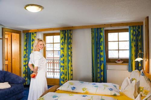 a woman standing next to a bed in a room at Gasthof Zwieselstein in Sölden