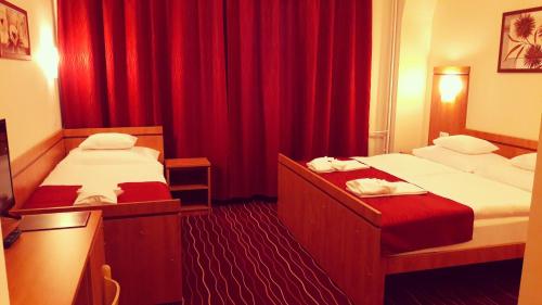 a hotel room with two beds and a red curtain at Diana Club Hotel in Budapest