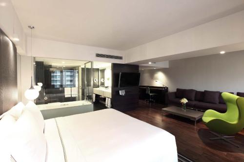 a bedroom with a bed and a living room with a couch at The Mira Hong Kong in Hong Kong