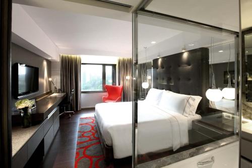 a hotel room with a large bed and a red chair at The Mira Hong Kong in Hong Kong
