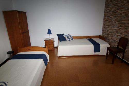 ヴィーラ・フランカ・ド・カンポにあるCasa da Cancelaのレンガの壁、ベッド2台が備わるベッドルーム1室が備わります。