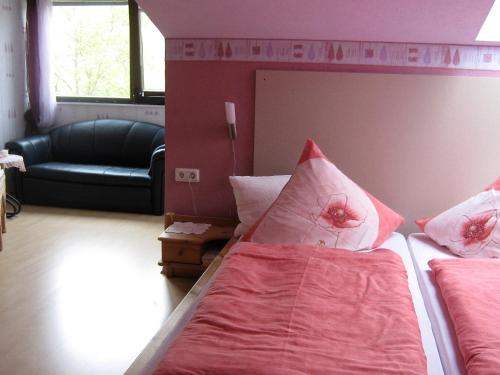 a bedroom with a bed with pink sheets and a couch at Gästehaus Schneider in Brauneberg