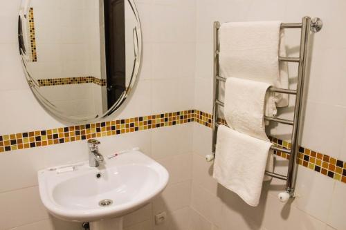 y baño con lavabo, espejo y toallas. en Paradise Hotel, en Saryaghash