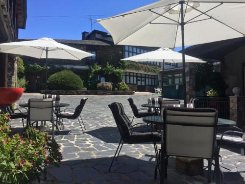 a patio with tables and chairs with umbrellas at Hotel O Forno in Salcedo