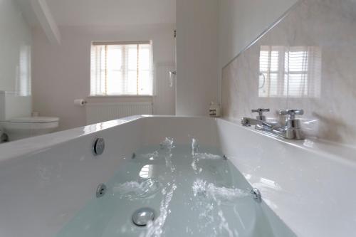 a large white bath tub in a bathroom at Blue Bell Cottage in Ollerton