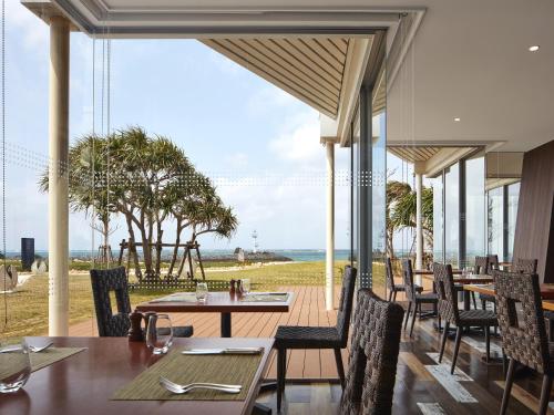 a restaurant with tables and chairs and a view of the ocean at Sheraton Okinawa Sunmarina Resort in Onna