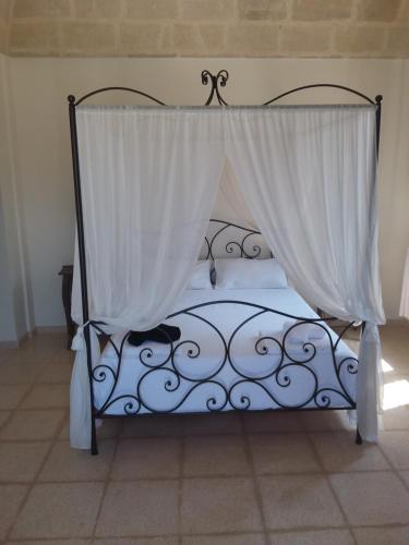 a bed with a canopy with a white curtain at Villa Pardonise- Puglia-Salento-Casa vacanze in Diso