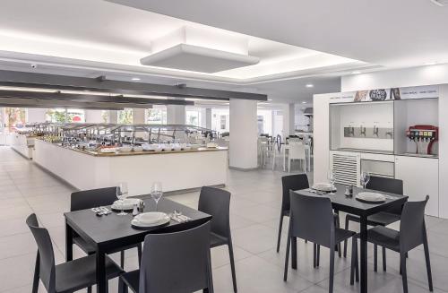 a dining room with tables and chairs and a kitchen at Hotel Vibra Mare Nostrum in Playa d'en Bossa
