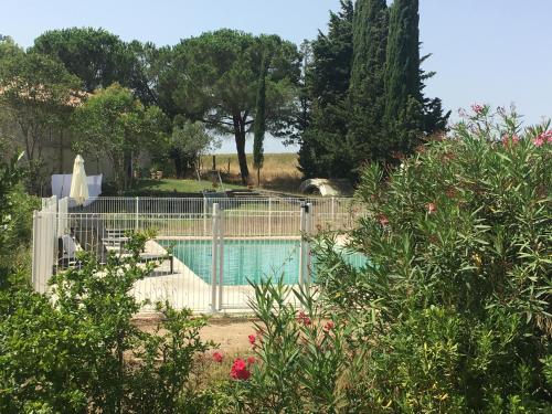 a fence around a swimming pool in a garden at Les Gites De La Serre in Saint-Thibéry