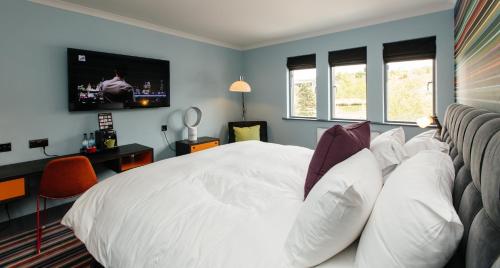 a bedroom with a white bed with a tv on the wall at Village Hotel Newcastle in Newcastle upon Tyne
