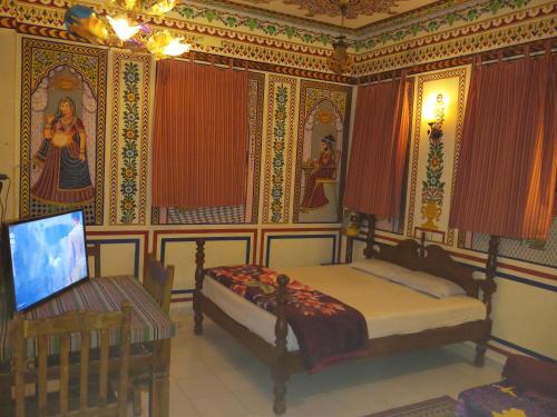 a bedroom with a bed and a table with a laptop at Hotel Shekhawati, A boutique stay in Mandāwa