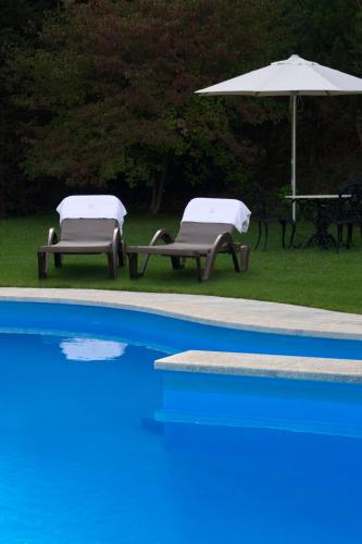 two chairs and an umbrella next to a swimming pool at Abba Xalet Suites Hotel in Sispony
