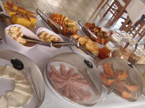 a table topped with plates of pastries and other foods at Hotel Miranelli in Barbacena