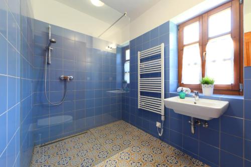 a blue tiled bathroom with a sink and a shower at Arácsi Vendégház in Balatonfüred