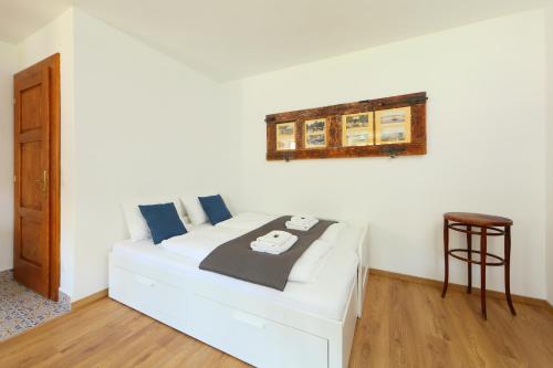 a white bed in a room with a stool at Arácsi Vendégház in Balatonfüred