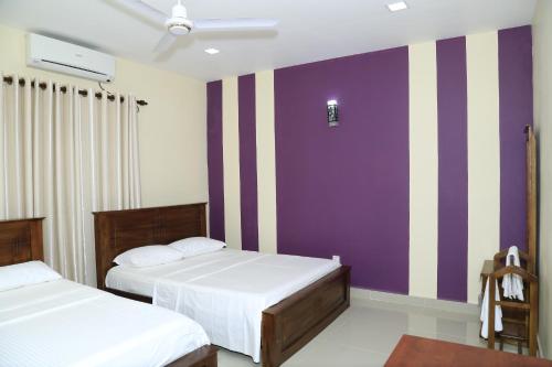 a bedroom with two beds and purple and white stripes at Superior rest in Jaffna