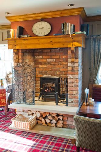 a brick fireplace with a clock on top of it at Pine Marten, Dunbar by Marston's Inns in Dunbar