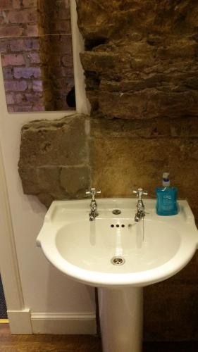 a white sink in a bathroom with a stone wall at Royal Mile Balconies by the Castle in Edinburgh