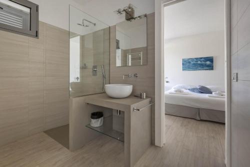 łazienka z umywalką, lustrem i łóżkiem w obiekcie Villa Sogno Bianco by BarbarHouse w mieście Ostuni