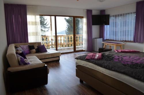a bedroom with a bed and a couch and a balcony at EldoSport Hotel in Dospat