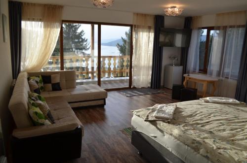 a bedroom with a bed and a couch and a balcony at EldoSport Hotel in Dospat