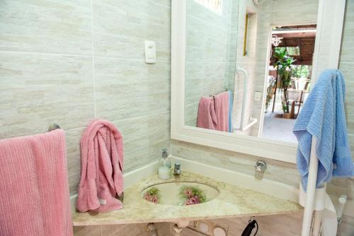 baño con lavabo con toallas rosas y espejo en Casa do Jardim, en Río de Janeiro