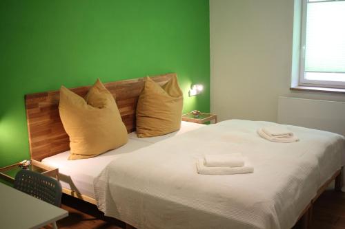 ein grünes Schlafzimmer mit einem Bett mit zwei Handtüchern darauf in der Unterkunft Wein und Stein in Randersacker