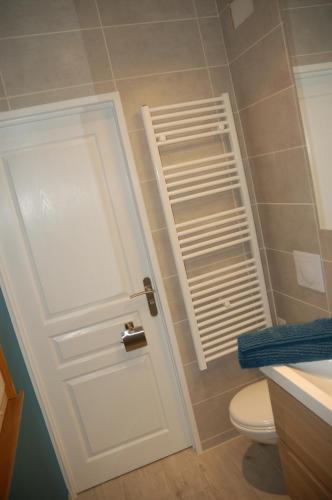 a bathroom with a white door next to a toilet at L'Horizon des Landes in Doazit