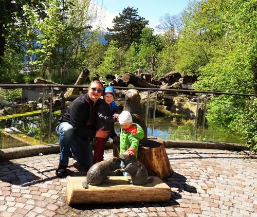 a man and two children standing next to a bear statue at Pension Alpengruss in Gerlos
