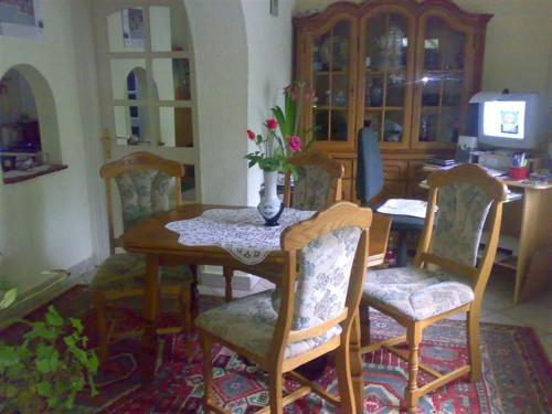 a dining room table and chairs with a vase of flowers on it at Árnyas Vendégház in Hajdúszoboszló