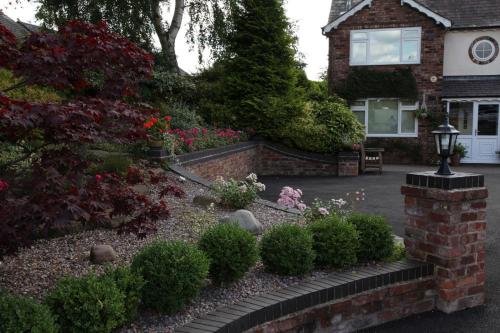 um jardim em frente a uma casa com flores em The Hinton Guest House em Knutsford