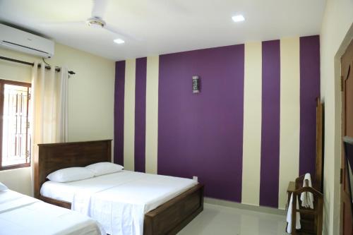 a bedroom with two beds and a purple and white wall at Superior rest in Jaffna