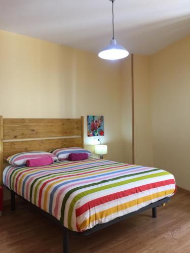 a bedroom with a bed with a colorful striped blanket at Apartamento Cuarto Real de Santo Domingo in Granada