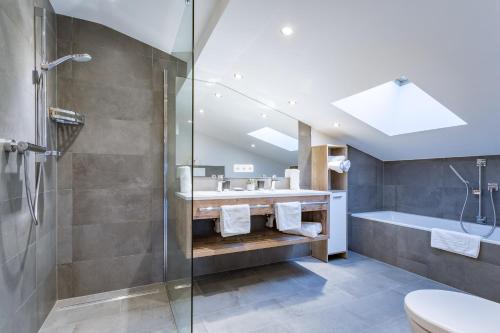 a bathroom with a shower and a sink and a tub at Active Apartments in Maria Alm am Steinernen Meer