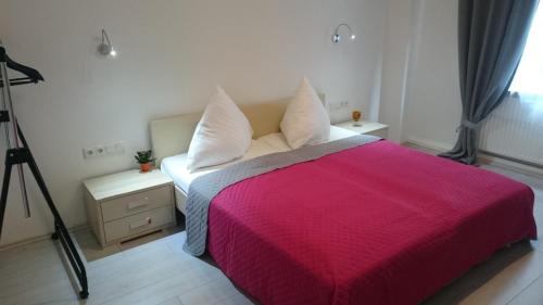 ein Schlafzimmer mit einem Bett mit einer roten Decke und einer Kamera in der Unterkunft AVI City Apartments GoodHouse in Düsseldorf